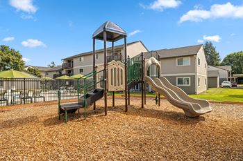 A playground with a slide, swings, and a tower structure.